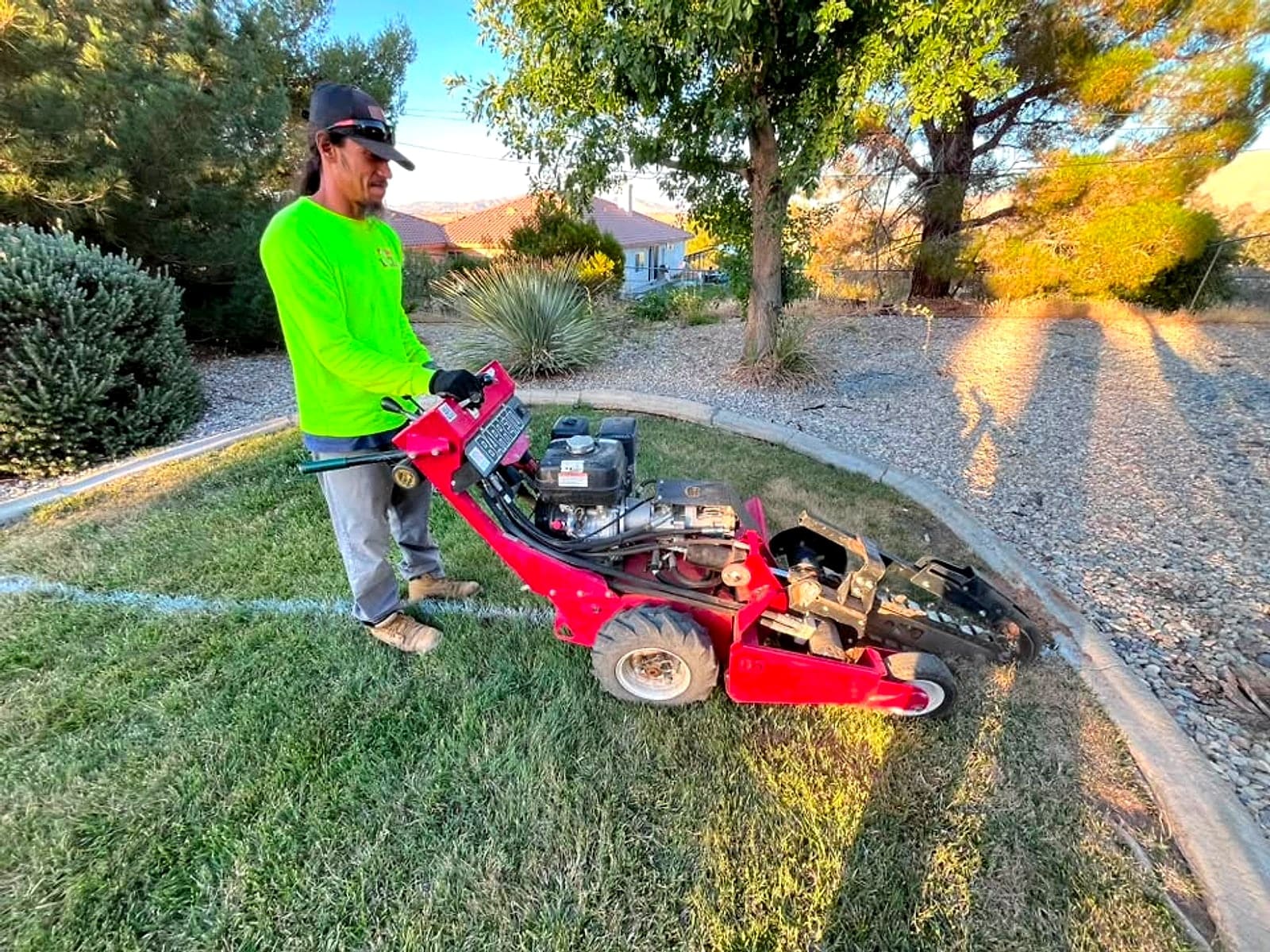 Crew member in a lime hi-vis shirt running a trencher along a string line