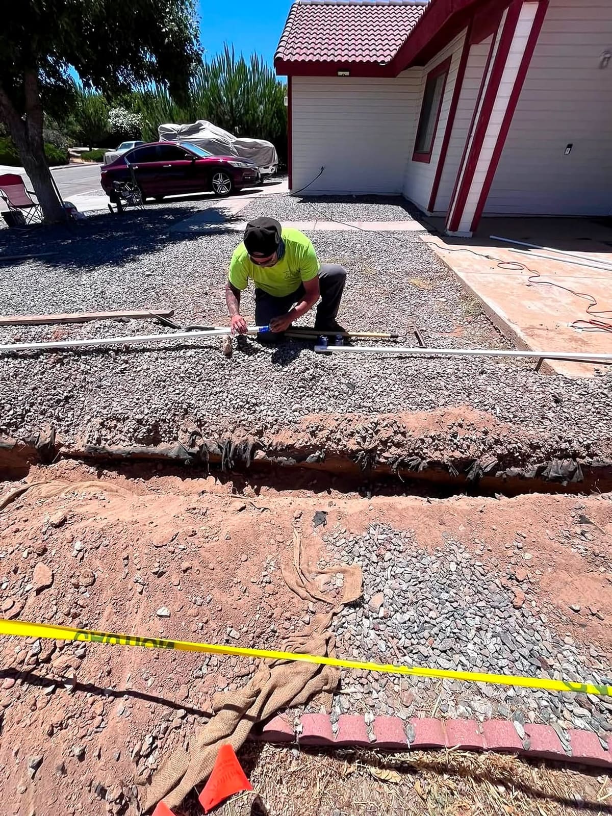 Crew member laying irrigation pipe in a gravel front yard