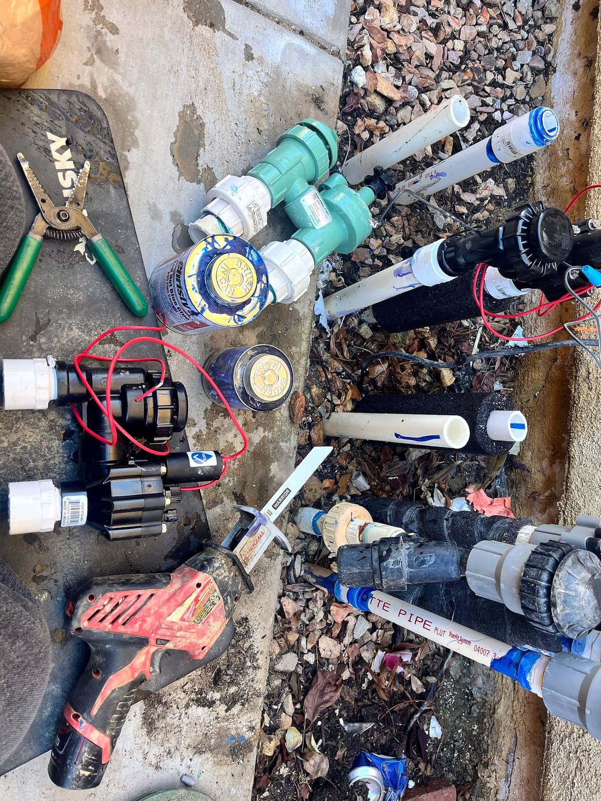 Irrigation valves, sprinkler heads and tools laid out on a job