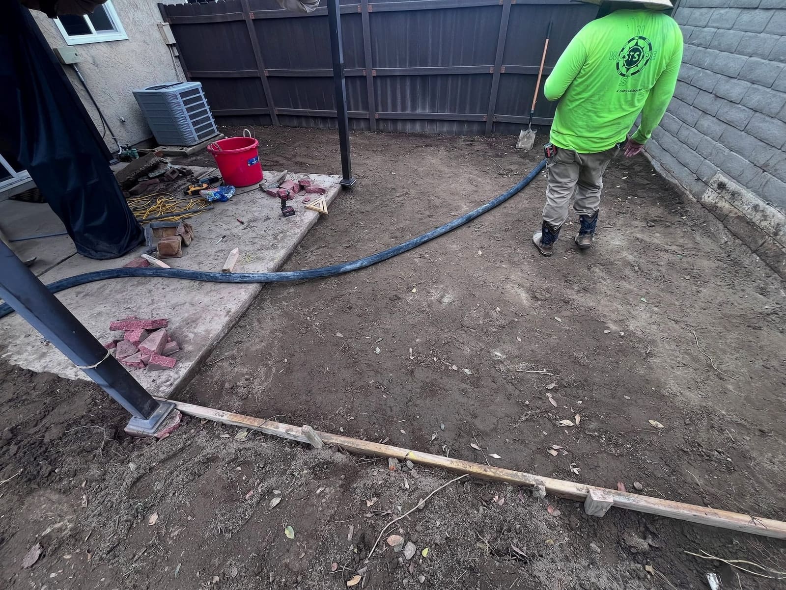 Crew member in a lime shirt prepping a backyard for new work